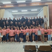 antigos alunos do curso de sargentos da turma de 1982 com suas respectivas esposas, postos no palco do auditório da escola