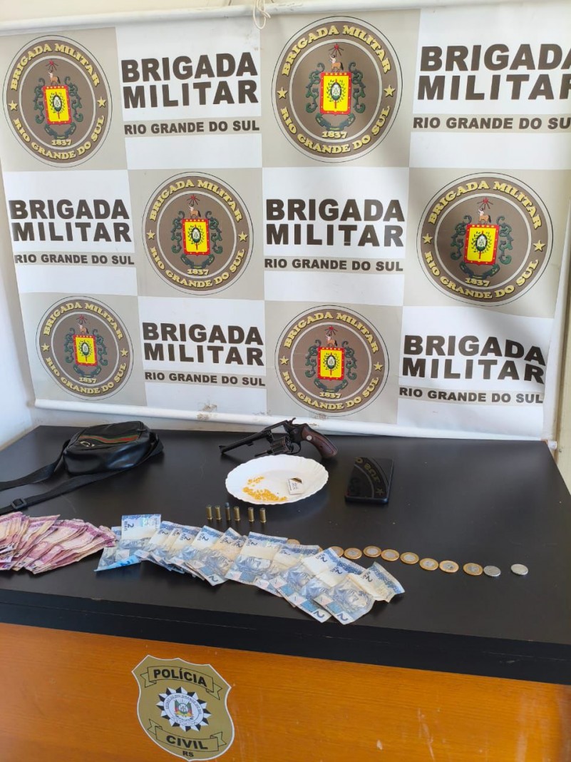Na foto contém um revólver, dinheiro e dinheiro