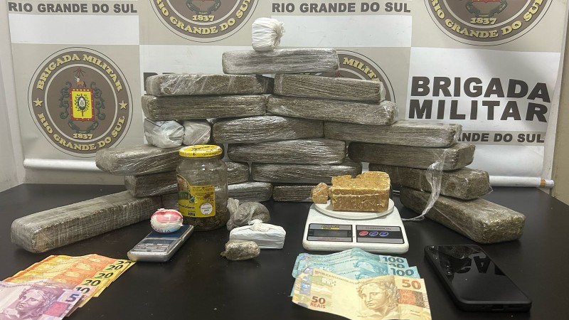 Na foto contém vários tabletes de maconha, cocaína e crack, balança de precisão e dinheiro