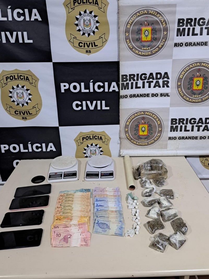 Material apreendido em frente ao banner da Polícia Civil e da Brigada Militar.