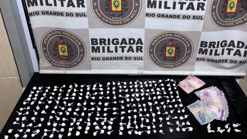 Porções da droga que foi apreendida sob uma mesa em frente ao banner da BM