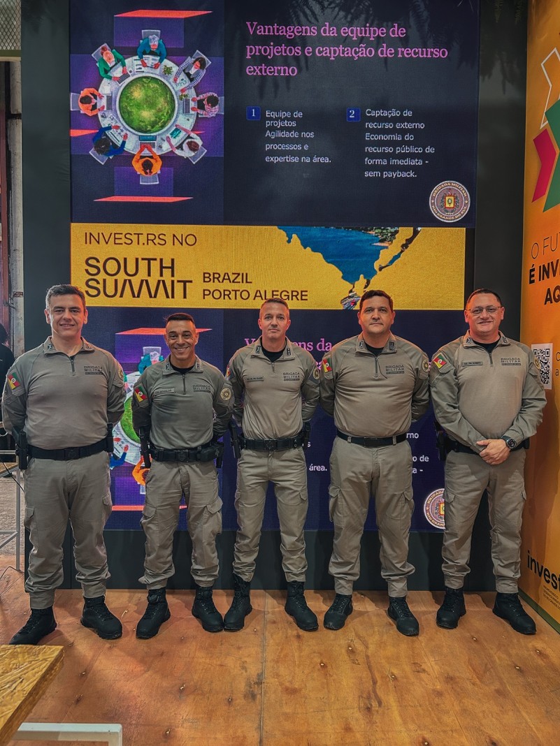 Foto mostra oficiais da Brigada Militar perfilados em frente ao painel onde aconteceu a apresentação.