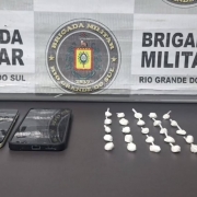 Banner da BM junto de celulares e drogas
