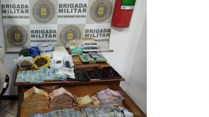 Várias de notas de dinheiro, entorpecentes, balanças de precisão, munições em cima de uma mesa