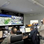 Foto mostra o comandante do Copom na sala de monitoramento assistindo às câmeras da cidade espelhadas em um grande monitor