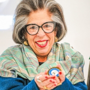senhora, sorridente, segurando uma moeda comemorativa nas mãos