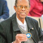 Senhor, sorridente, segurando uma moeda comemorativa em suas mãos