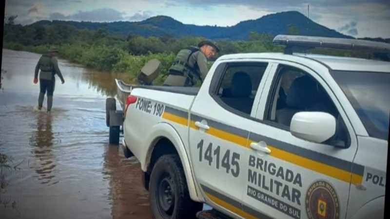 Imagem mostra camionete da BM conduzindo um barco em uma via alagada e seguindo para efetuar o resgate de vítimas
