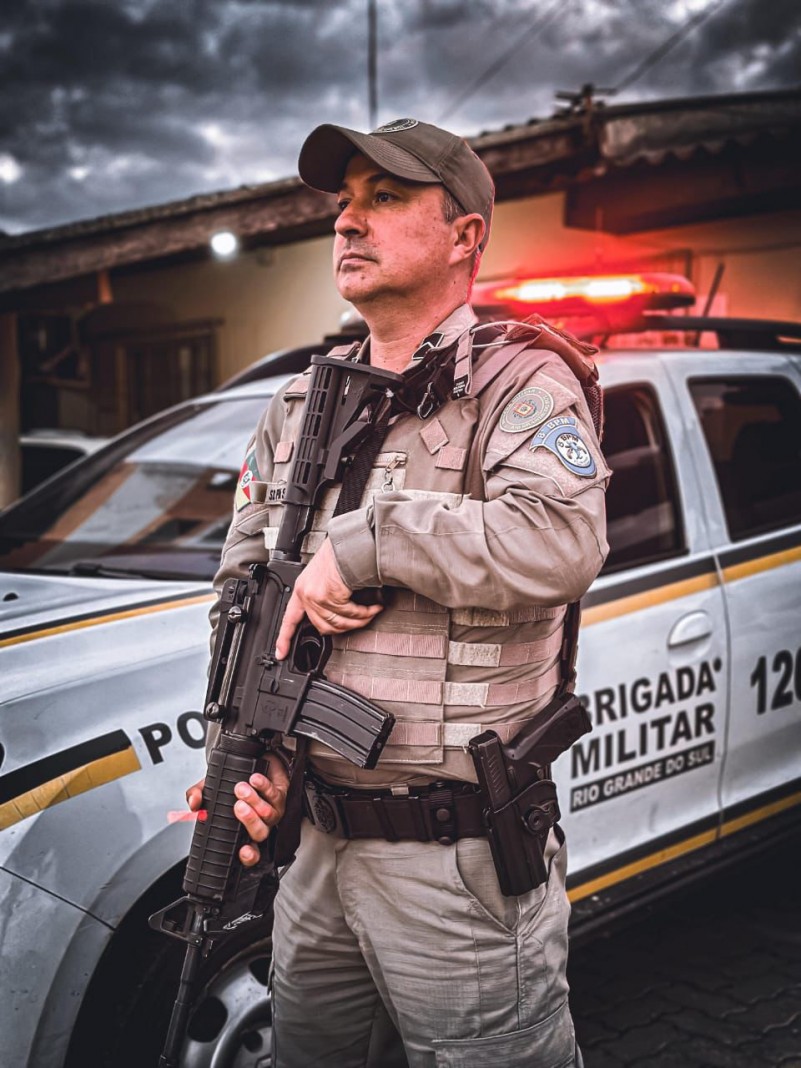 Policial militar em frente a uma viatura