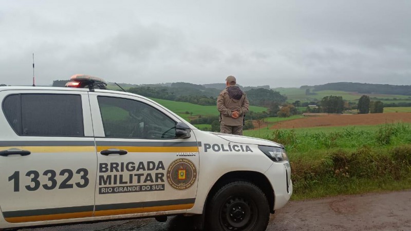 Na foto uma viatura policial e um policial no interior