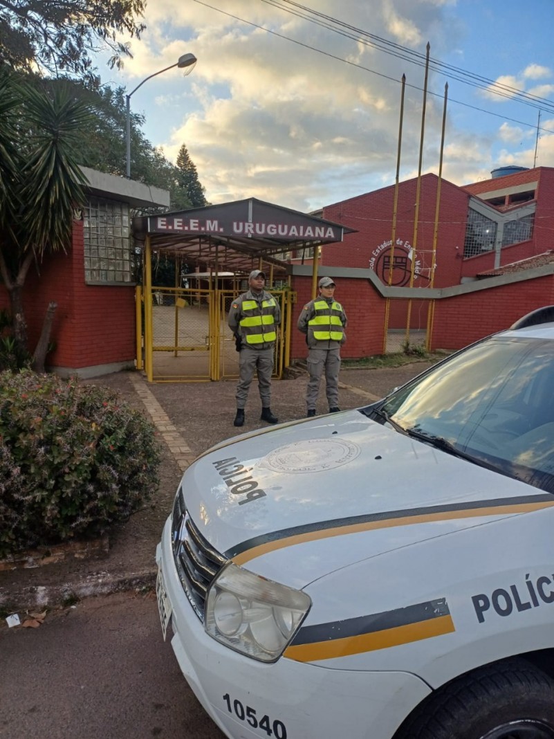 Foto mostra dupla de policiais militares posicionados em frente ao port&atilde;o de uma escola
