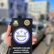Folder da Patrulha Maria da Penha, na cor preta com a cidade ao fundo