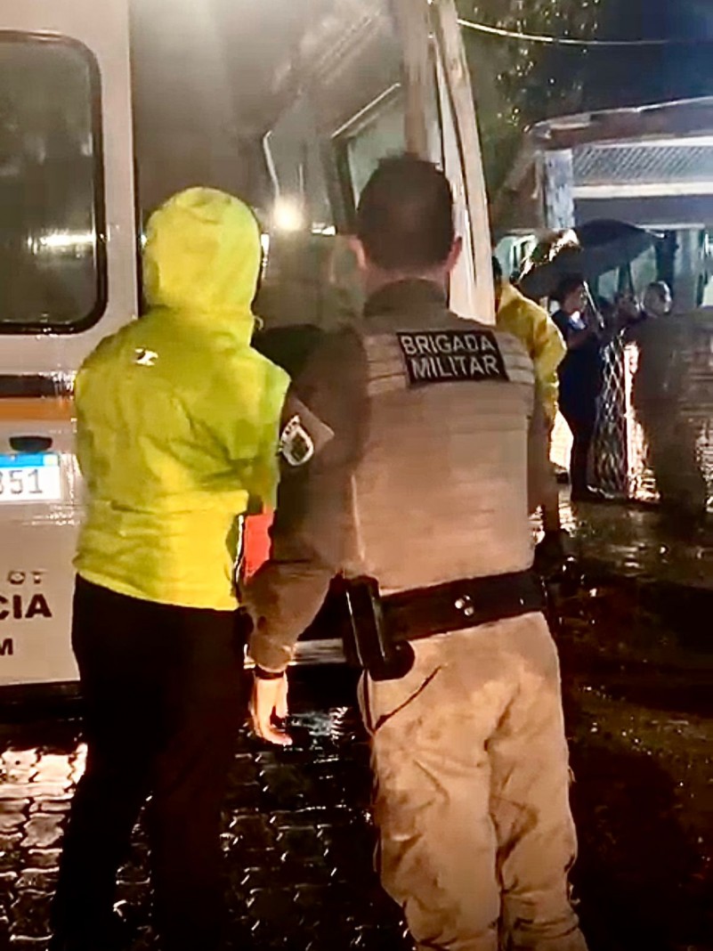 Na imagem policial militar juntamente a defesa civil do munic&iacute;pio auxiliando na remo&ccedil;&atilde;o das fam&iacute;lias atingidas pela enchente do Rio Jacu&iacute; ao fundo micro &ocirc;nibus da brigada militar.