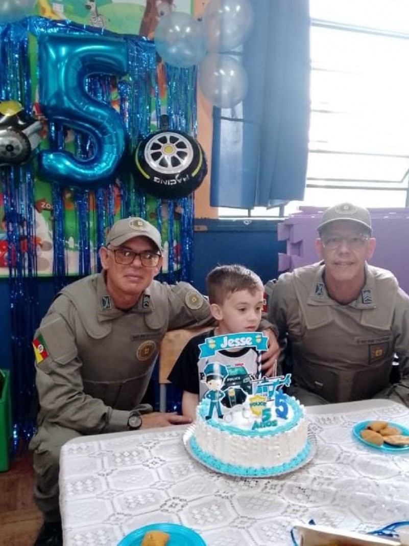 Na imagem policiais militares ao lado no aniversariante Jess&eacute; na decora&ccedil;&atilde;o de pol&iacute;cia na sala de aula de sua escola